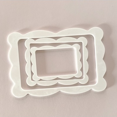 Três moldes de plástico branco com bordas onduladas sobre fundo rosa