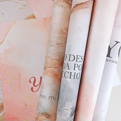 Rolos de papel decorativo com padrões marmorizados e texto parcial em tons neutros