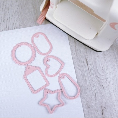 Conjunto de moldes metálicos rosa para recortes e máquina de corte branca em fundo claro