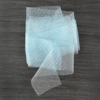 Lenço azul claro com pontos brancos sobre superfície de madeira escura