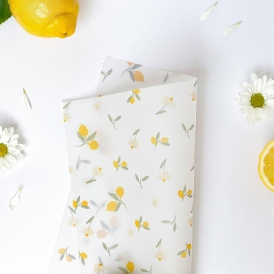 Papel vegetal branco decorado com padrão de limões e folhas em fundo branco