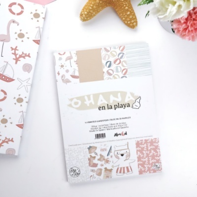 Bloco de papel decorativo com padrões temáticos de praia, em cores bege, azul, laranja e rosa, sobre fundo branco com decoração de estrela-do-mar e flores.