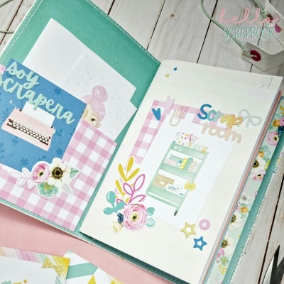 Pasta verde aberta com páginas decoradas de scrapbooking em rosa e branco, texto 