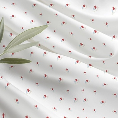 tecido branco com pequenas flores vermelhas e azul com folhagem verde em cima