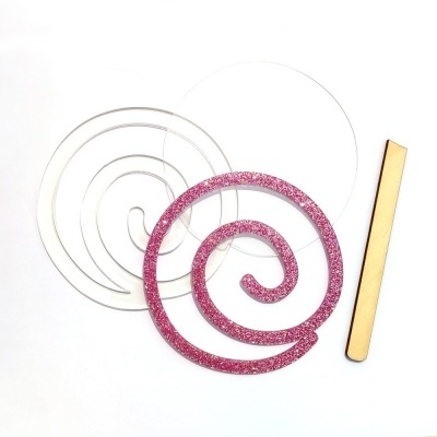 Três espirais em materiais rosa brilhante, translúcido e metálico dourado sobre fundo branco