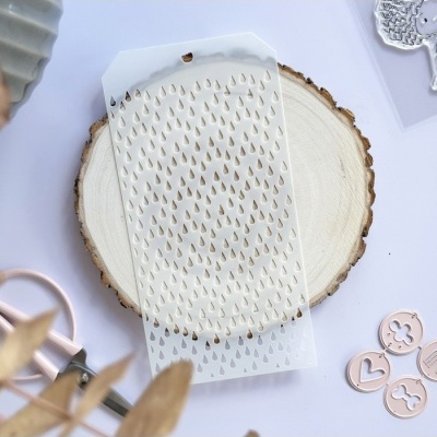 Stencil branco transparente com padrão de gotas recortadas sobre base redonda de madeira