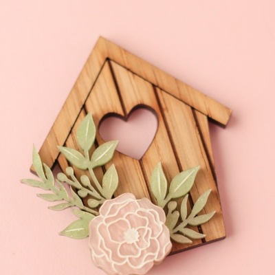 Broche decorativo de madeira em forma de casa com coração e flores
