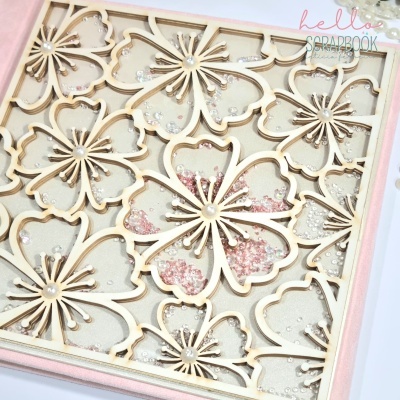 Quadro decorativo com flores de madeira clara e pedras translúcidas em moldura rosa