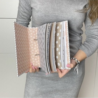 Pessoa a segurar álbum com páginas decoradas coloridas em tons pastel