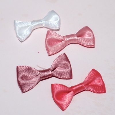 Quatro laços pequenos de seda em várias cores sobre fundo claro