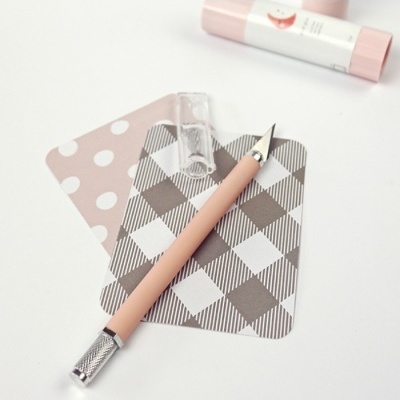 Caneta de corte rosa claro com lâmina metálica sobre cartões decorativos