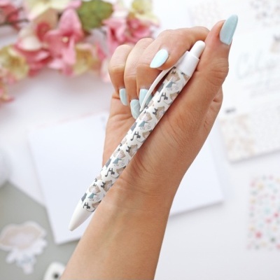 Caneta esferográfica com padrão de cães em tons de cinza e bege na mão