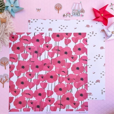 Dois papéis estampados com padrões florais e pequenos elementos decorativos sobre superfície rosa