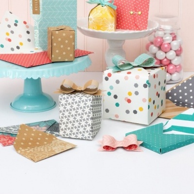Pequenos presentes coloridos com vários padrões decorativos em suportes de bolo e frasco com gomas.