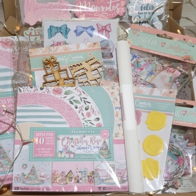 Conjunto de scrapbooking com papéis decorados, adesivos, recortes em madeira e carimbos embalados em plástico
