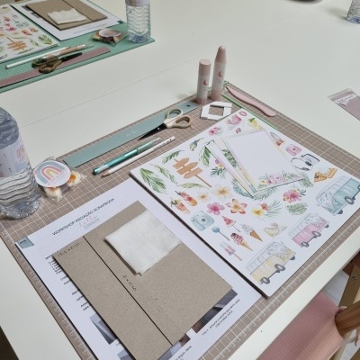 Mesa com materiais de papelaria para trabalhos manuais, incluindo folhas, tesouras, cola e régua.