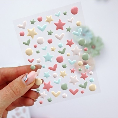 Folha de autocolantes 3D coloridos com estrelas, corações e círculos segurarada à mão