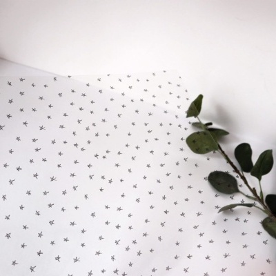 Papel branco com estrelas pretas e ramo verde