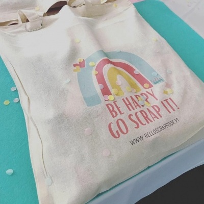 Mala de tecido bege com desenho de arco-íris e texto motivacional em tons pastel