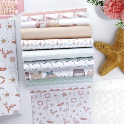 Papéis decorativos com padrões de animais e objetos em tons pastel, ao lado de uma estrela-do-mar amarela e uma flor cor-de-rosa