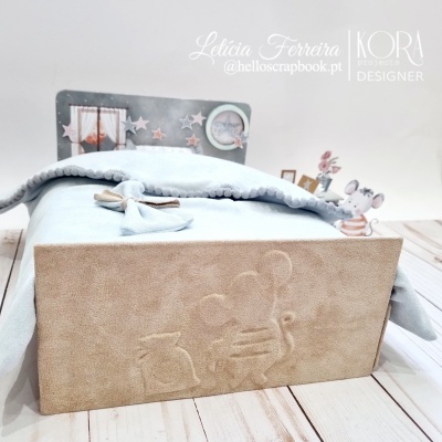 Cama de brinquedo com roupa azul clara e painel com estrelas cinza e rato