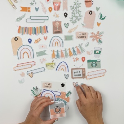 Cartões decorativos coloridos com mãos a organizar sobre mesa branca