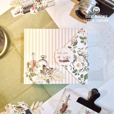 Elementos decorativos em papel com temas musicais, florais e relógio sobre mesa com câmara antiga e mola preta