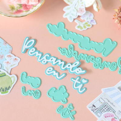 Moldes de corte azuis com frases em português sobre superfície rosa e recortes decorativos