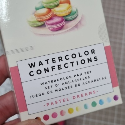 Caixa de aguarelas com macarons coloridos e texto