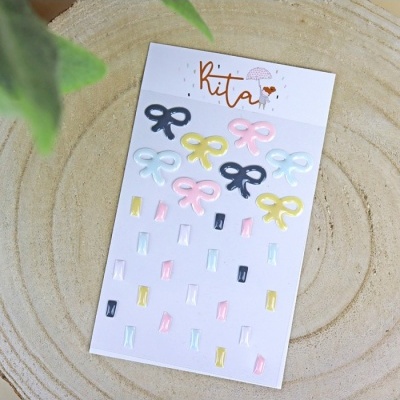 Cartão com adesivos de laços e retângulos coloridos sobre madeira clara