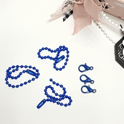 Acessórios azuis para bijuteria com correntes e fechos sobre fundo branco com tecido decorativo