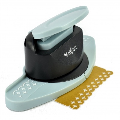 Furador de papel cinza e preto com padrão decorativo a cortar papel dourado