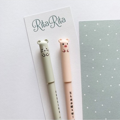 Dois marcadores de texto com tampas ursinho verde e rosa sobre cartão 'Rita Rita' e folha verde com bolinhas brancas