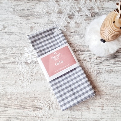 Guardanapo xadrez cinza e branco com etiqueta DREAM FOLIO num ambiente decorado com flocos de neve e rena de madeira