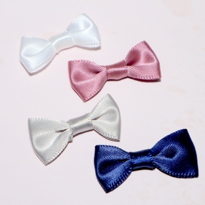 Quatro laços pequenos de tecido coloridos em branco, rosa, cinzento claro e azul escuro