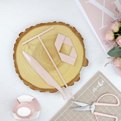 Itens para artesanato rosa pastel sobre base de madeira redonda.