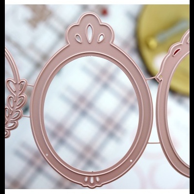 Moldura decorativa redonda rosa com detalhes recortados sobre superfície xadrez