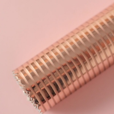 Rolo de papel de embrulho metálico cobre com padrão de riscas sobre fundo rosa