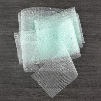 Lenço branco de tecido tulle com brilhos dourados sobre fundo de madeira escura