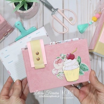 Carteira rosa com decoração de cupcake e agenda com tema de gelado sobre mesa de madeira