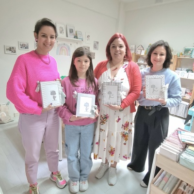 Quatro pessoas segurando quadros com imagens infantis em ambiente interior