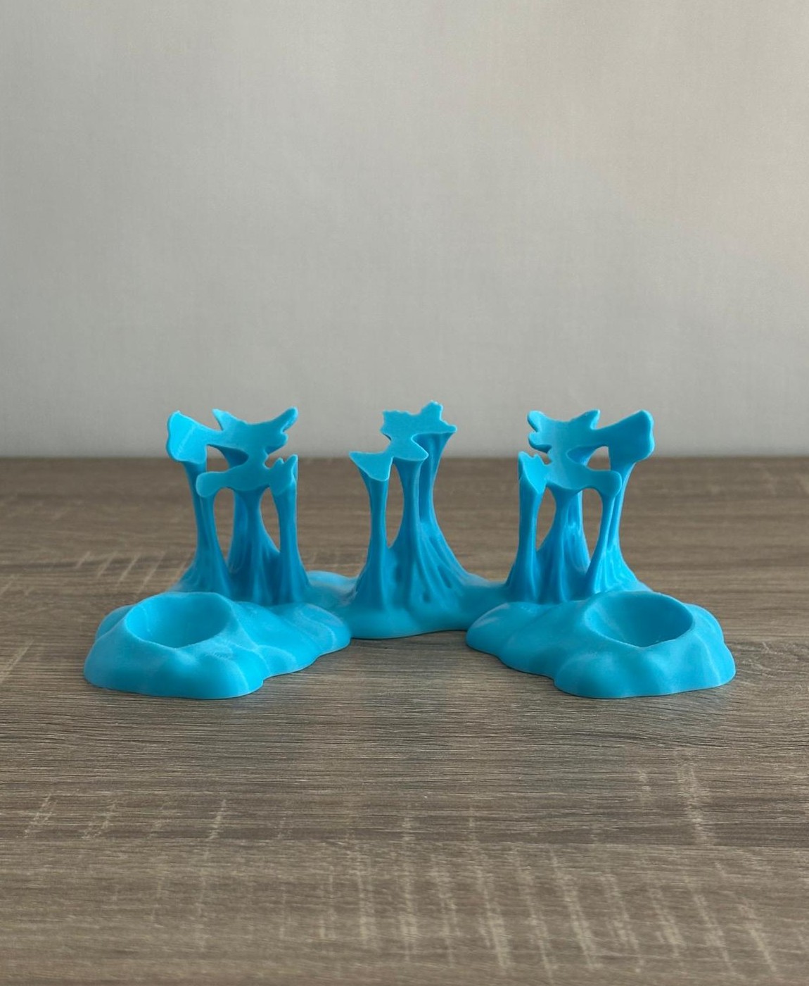 Três suportes azuis em plástico com formas orgânicas e recortes únicos