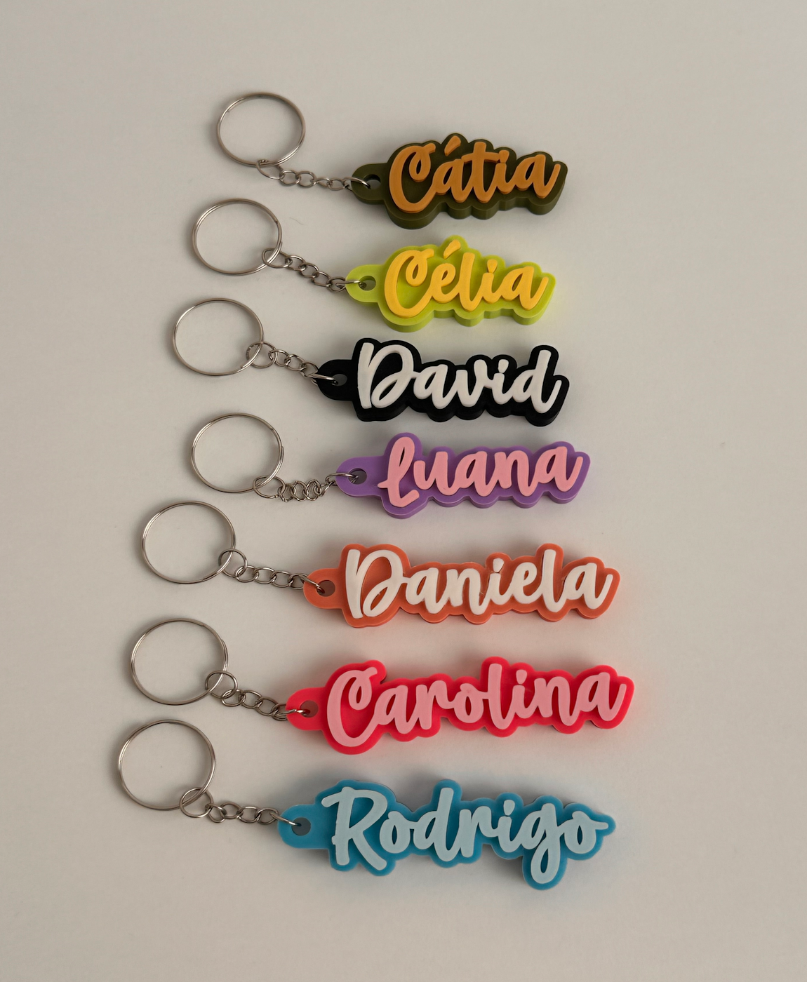 Seis porta-chaves coloridos com nomes em letras grandes.