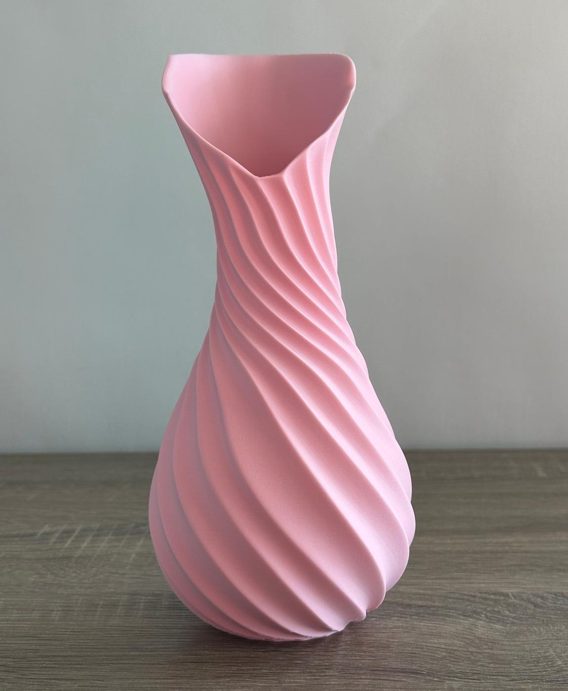 Vaso cor-de-rosa com textura espiral em mesa de madeira