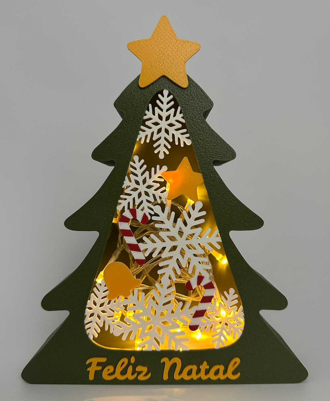 Decoração de Natal em forma de árvore verde com estrela amarela e flocos de neve com luzes amarelas