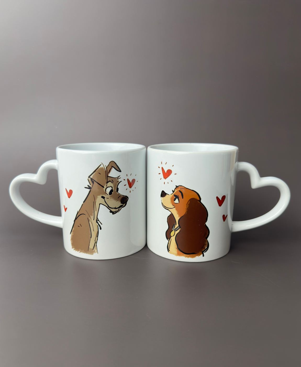 Duas canecas brancas com punhos em forma de coração e ilustrações de cães com corações vermelhos