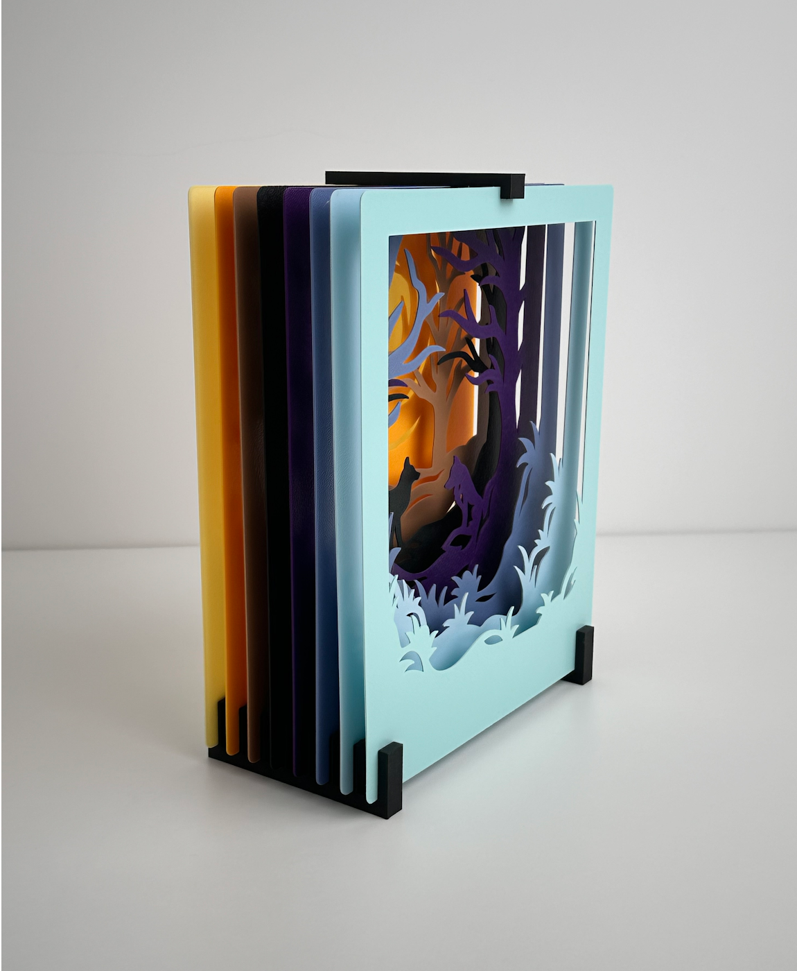Livro artesanal com capas coloridas, design de floresta e lobos recortados em papel azul
