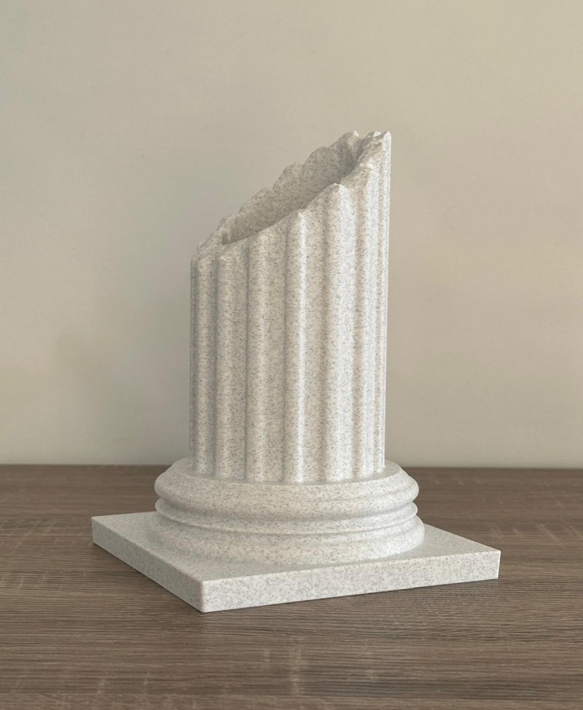 Coluna decorativa branca com base quadrada e topo quebrado sobre madeira