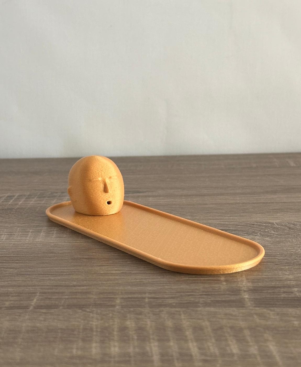 Tabuleiro castanho claro com peça esférica decorada com rosto sorridente