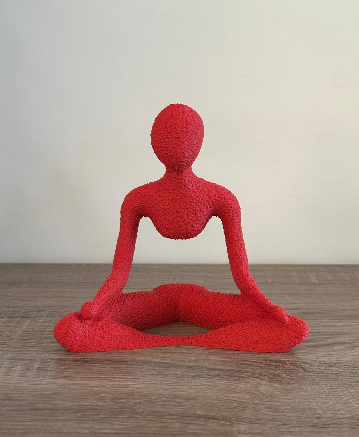 Figura decorativa vermelha em tecido felpudo sentada em posição de meditação